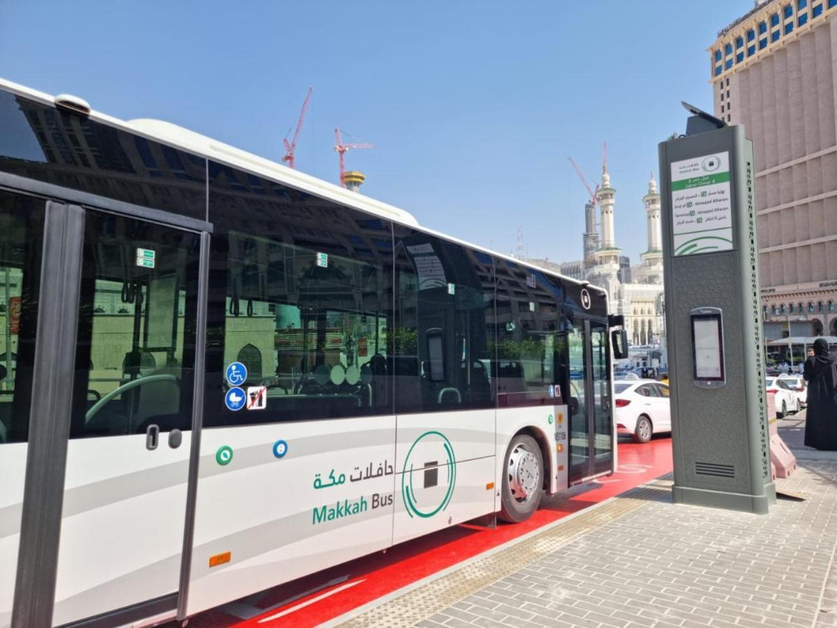 Jabal Omar Hyatt Regency Makkah Hotel Mekka Kültér fotó The photo shows a public bus labeled "Makkah Bus," parked at a designated bus stop. The bus has a modern design and is predominantly white, with green accents. In the background, there are tall buildings and construction cranes, indicating a busy urb
