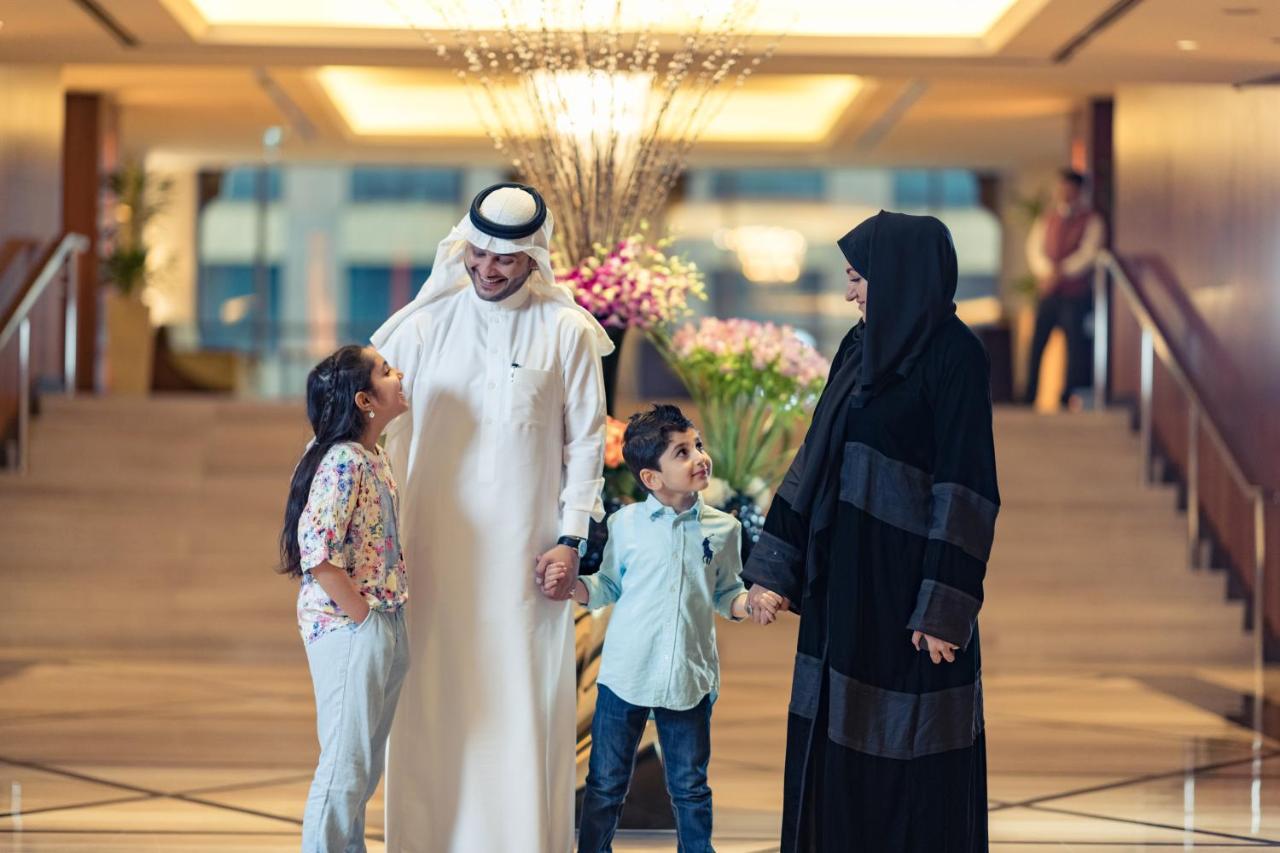 Jabal Omar Hyatt Regency Makkah Hotel Mekka Kültér fotó The photo shows a family in a hotel lobby. There are two children, a boy and a girl, standing between their parents. The girl is smiling and looking up at her father, who is wearing traditional white attire and a headscarf. The boy is also smiling an