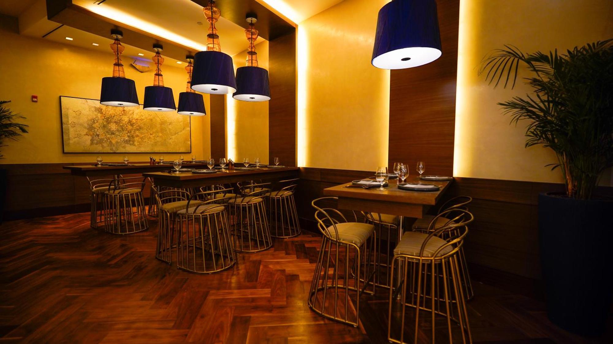 Jabal Omar Hyatt Regency Makkah Hotel Mekka Kültér fotó The photo shows an elegantly designed restaurant interior. It features stylish seating arrangements with gold wire chairs paired with tables. The ambient lighting is warm, with a mix of recessed lights and pendant lamps that have blue shades, creatin