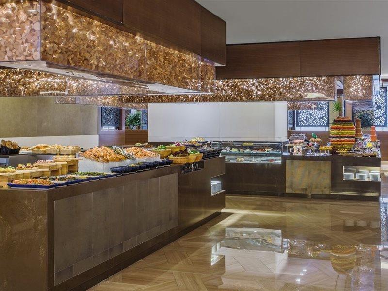 Jabal Omar Hyatt Regency Makkah Hotel Mekka Kültér fotó The photo shows a stylish buffet area, likely in a restaurant or hotel. There are several food displays arranged on long tables with shiny surfaces. The buffet features a variety of items, which may include pastries, bread, and other dishes. The area