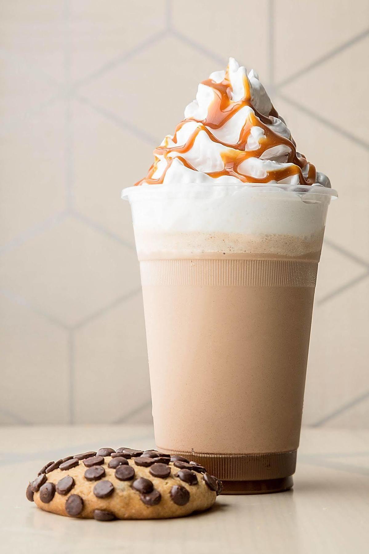 Jabal Omar Hyatt Regency Makkah Hotel Mekka Kültér fotó The photo shows a tall cup of a creamy beverage, likely a milkshake or a blended coffee drink. The drink has a light brown color with a frothy top, which is topped with whipped cream. Drizzled over the whipped cream is a thick caramel sauce, adding a
