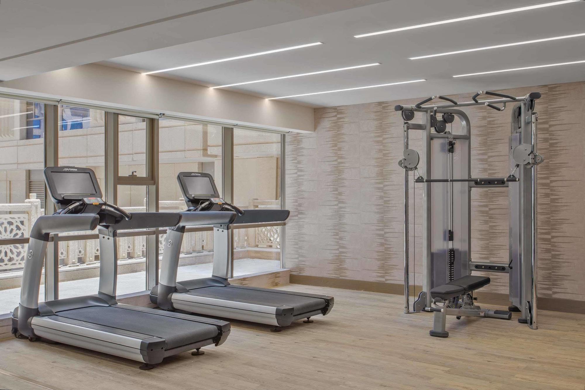 Jabal Omar Hyatt Regency Makkah Hotel Mekka Kültér fotó The photo shows a modern gym area featuring two treadmills positioned side by side. Next to them is a multi-functional gym machine designed for strength training, which includes various attachments for different exercises. The gym has a bright, airy 