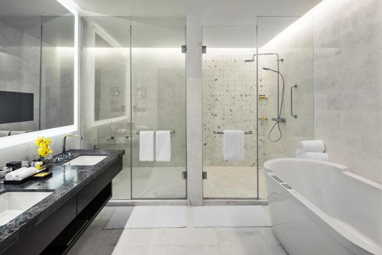 Jabal Omar Hyatt Regency Makkah Hotel Mekka Kültér fotó The photo shows a modern bathroom with a sleek design. It features a glass shower enclosure with a rainfall showerhead and a stylish bathtub. The floor and walls have a light-colored stone or tile finish, giving a clean and minimalist look. There's a