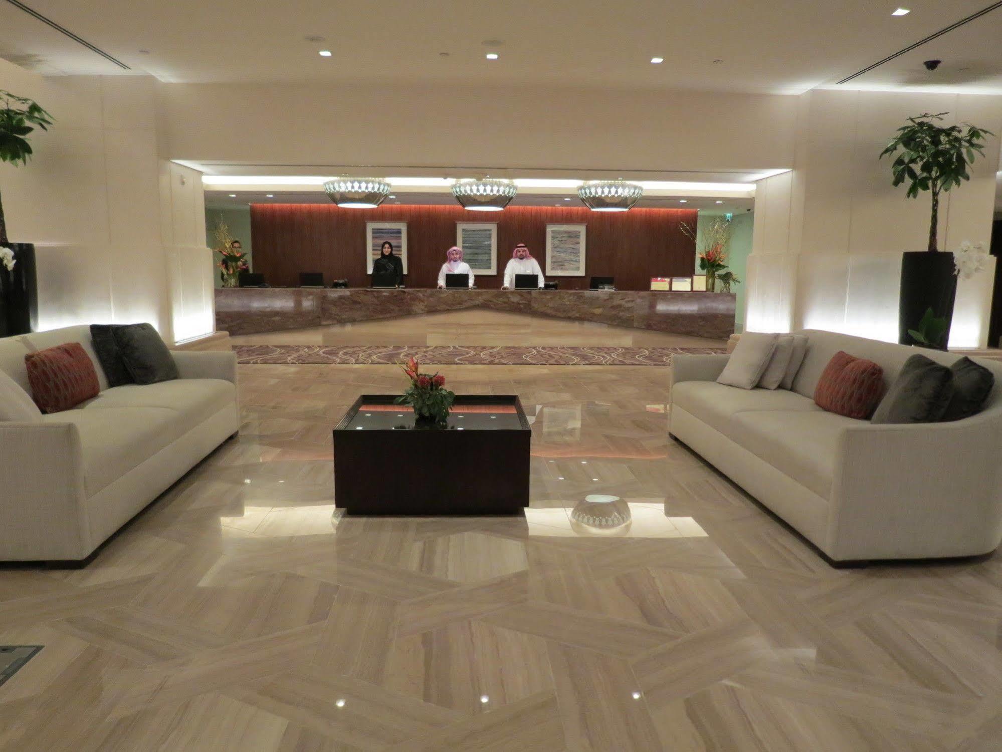 Jabal Omar Hyatt Regency Makkah Hotel Mekka Kültér fotó The photo shows a modern hotel lobby. In the foreground, there are two light-colored sofas with decorative pillows, positioned facing each other. A small coffee table with a plant sits between the sofas. 

In the background, there is a reception desk
